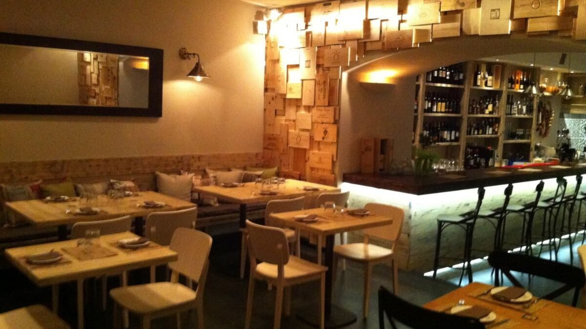 Cozy wine bar interior with glasses of wine, tapas-style dishes, and soft lighting.