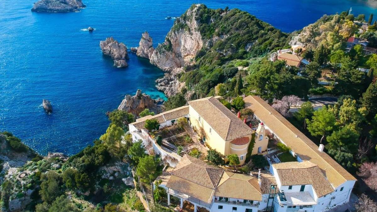 Hilltop monastery overlooking Paleokastritsa bay with panoramic view of sea, cliffs, and coastline.