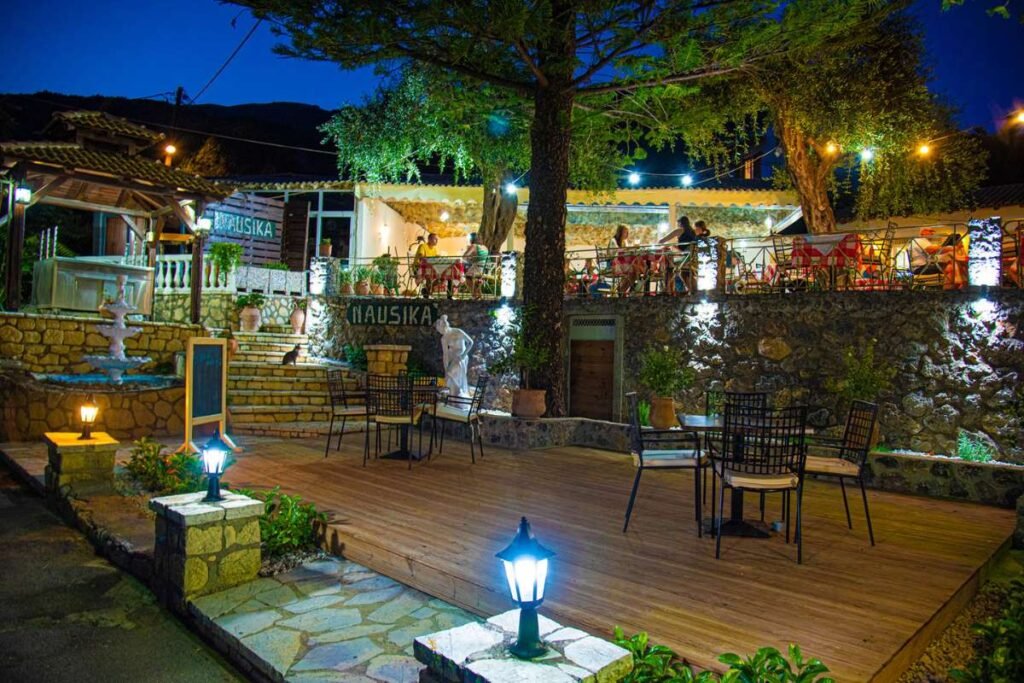 Seaside Greek taverna in Paleokastritsa with simple tables and traditional dishes near the water.