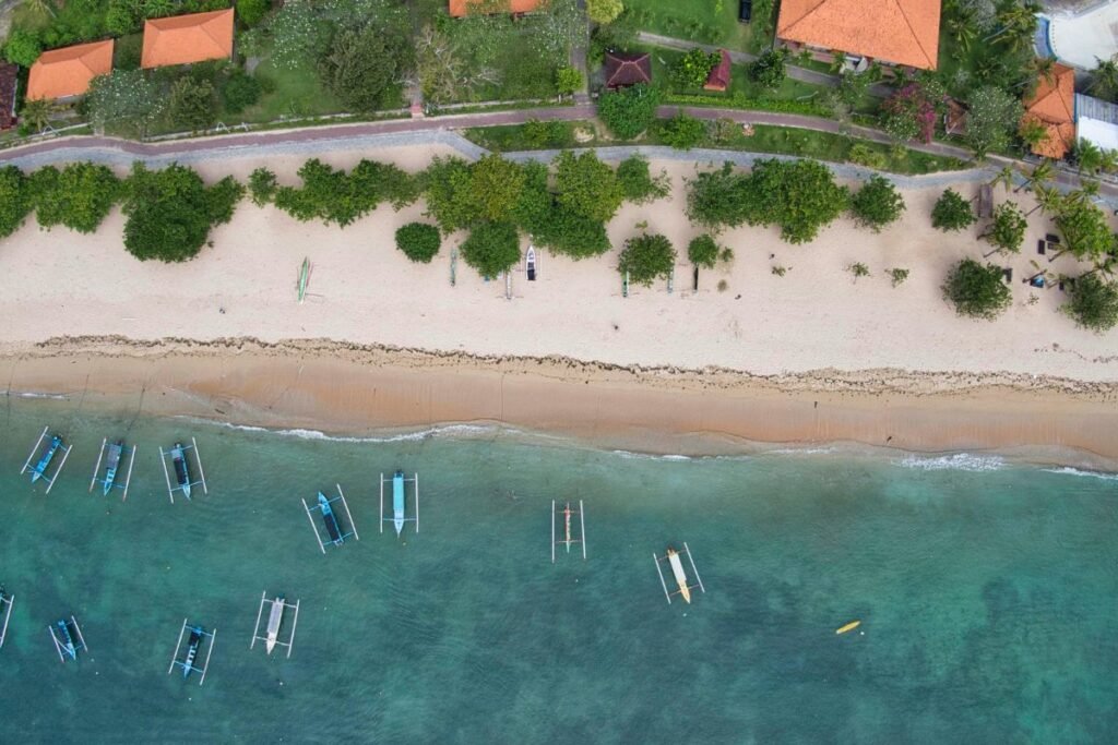Tranquil beach near Denpasar in Bali with palm trees, calm waves, and tropical sunset scenery”