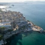Beautiful panoramic view of Corfu, Greece with turquoise sea, colorful coastal towns, and traditional Mediterranean architecture.