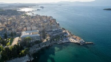 Beautiful panoramic view of Corfu, Greece with turquoise sea, colorful coastal towns, and traditional Mediterranean architecture.