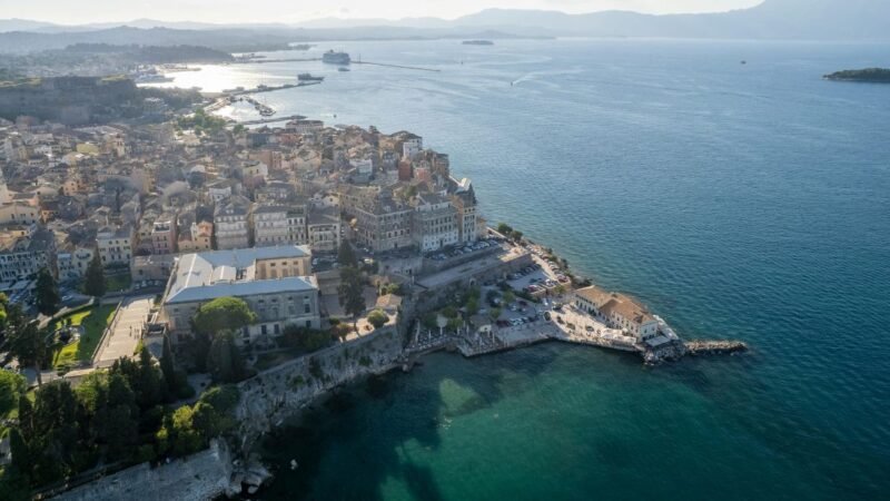 Beautiful panoramic view of Corfu, Greece with turquoise sea, colorful coastal towns, and traditional Mediterranean architecture.