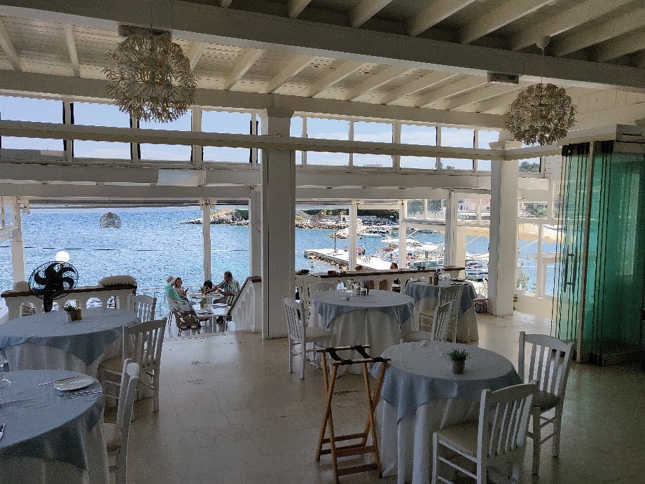 Elegant outdoor dining area at Kima Restaurant with tables facing the sea in Kassiopi, Corfu.