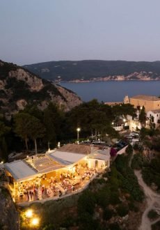 Chic restaurant terrace with candles and sea view at night in Corfu.