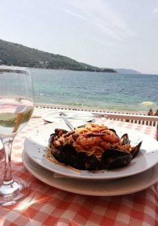 Seafood pasta served at Janis Taverna in Kassiopi with a picturesque sea view in the background.